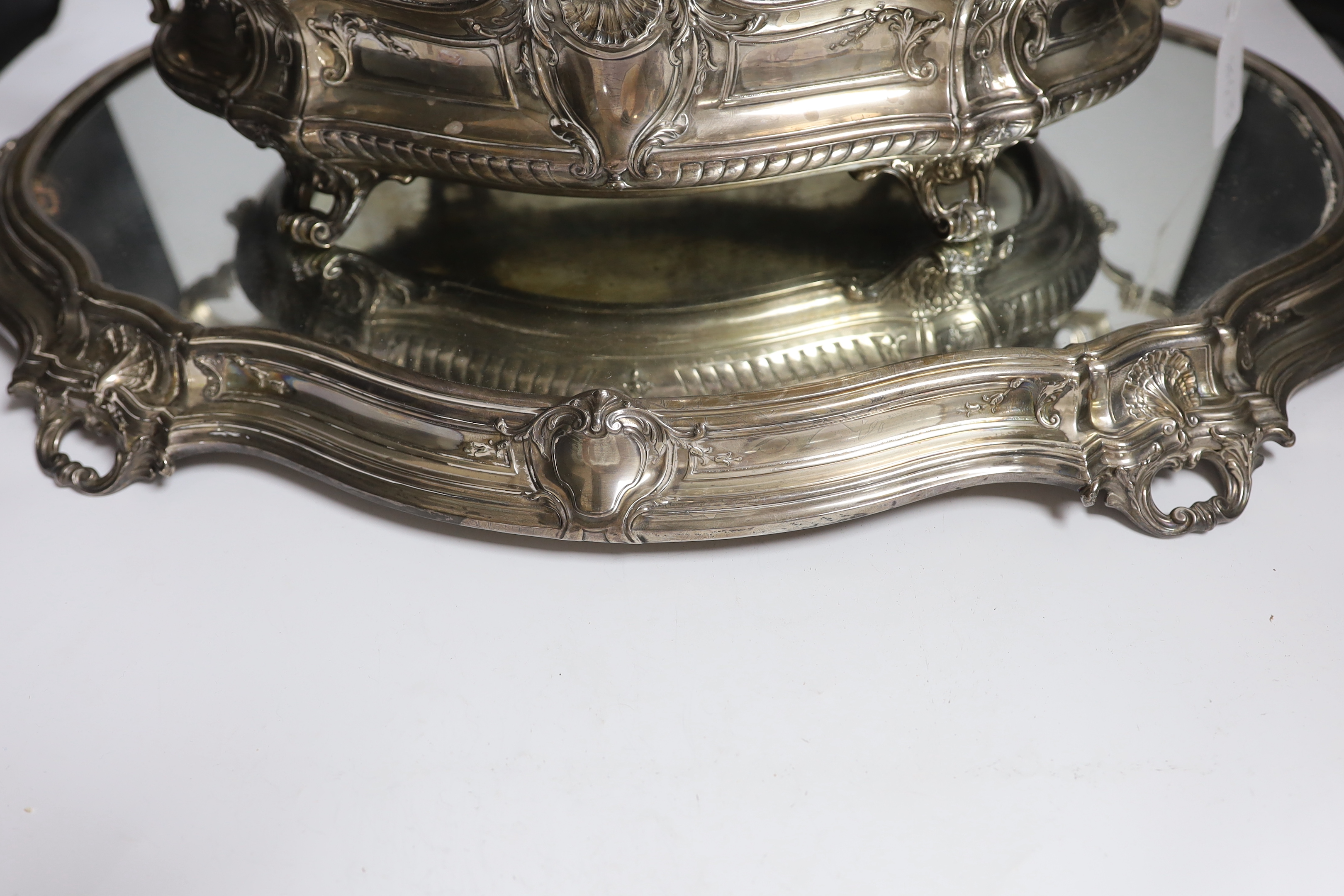 A large ornate Belgian? 800 standard white metal two handled oval centrepiece, 53cm, 46.1oz, with a base metal liner, on a similar 800 standard white metal mounted mirrored stand, 70cm.